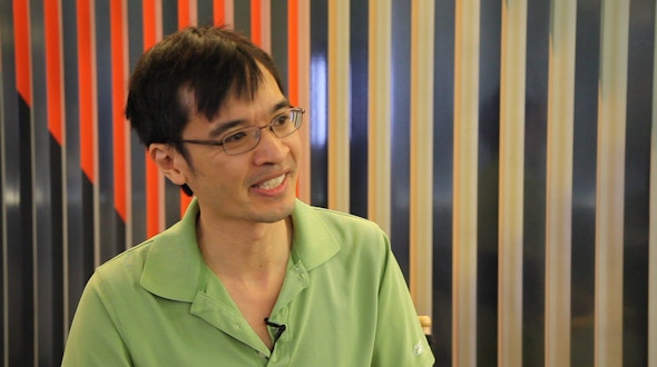 Terrence Tao talking in front of a wall with wooden slats