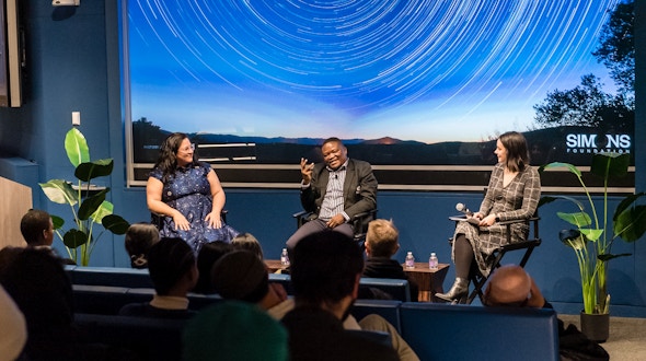Three people sitting in director's chairs in front of an audience.